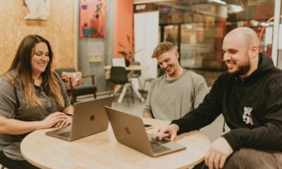 Three people collaborate around a table with laptops.