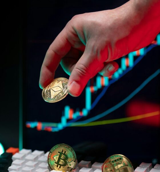 Hand holding ethereum with crypto graphs in background.