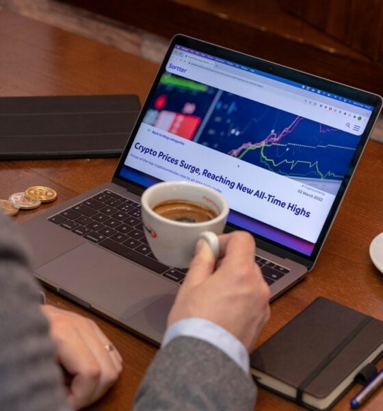 a man sitting at a table with a laptop and a cup of coffee