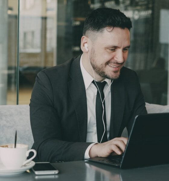 Man in suit working on laptop in cafe
