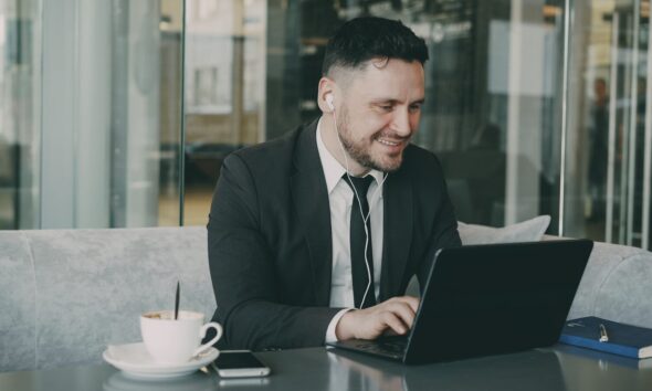 Man in suit working on laptop in cafe