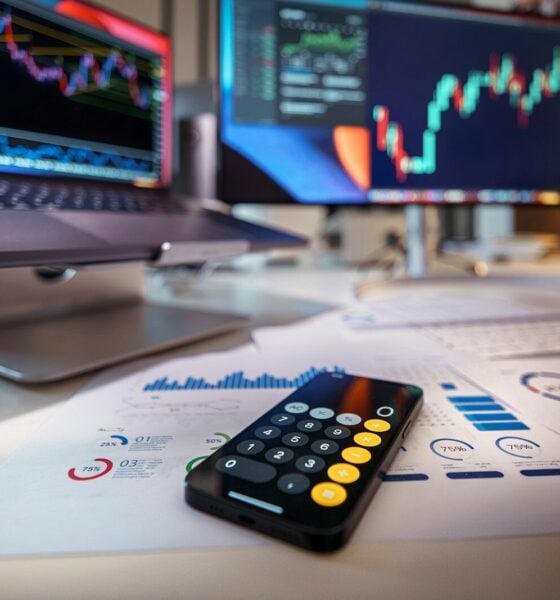 smartphone calculator on desk with financial charts behind