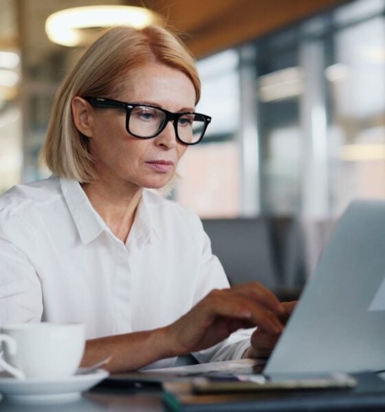 a woman sitting at a table using a laptop computer