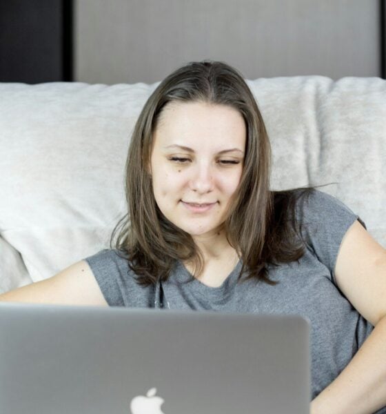 a woman sitting on a couch using a laptop computer