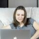 a woman sitting on a couch using a laptop computer