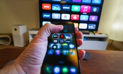 Hand holding smartphone controlling smart TV apps