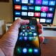 Hand holding smartphone controlling smart TV apps