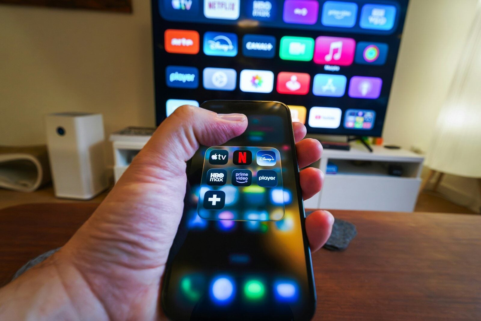 Hand holding smartphone controlling smart TV apps