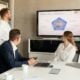 Three people in a meeting room looking at a presentation.