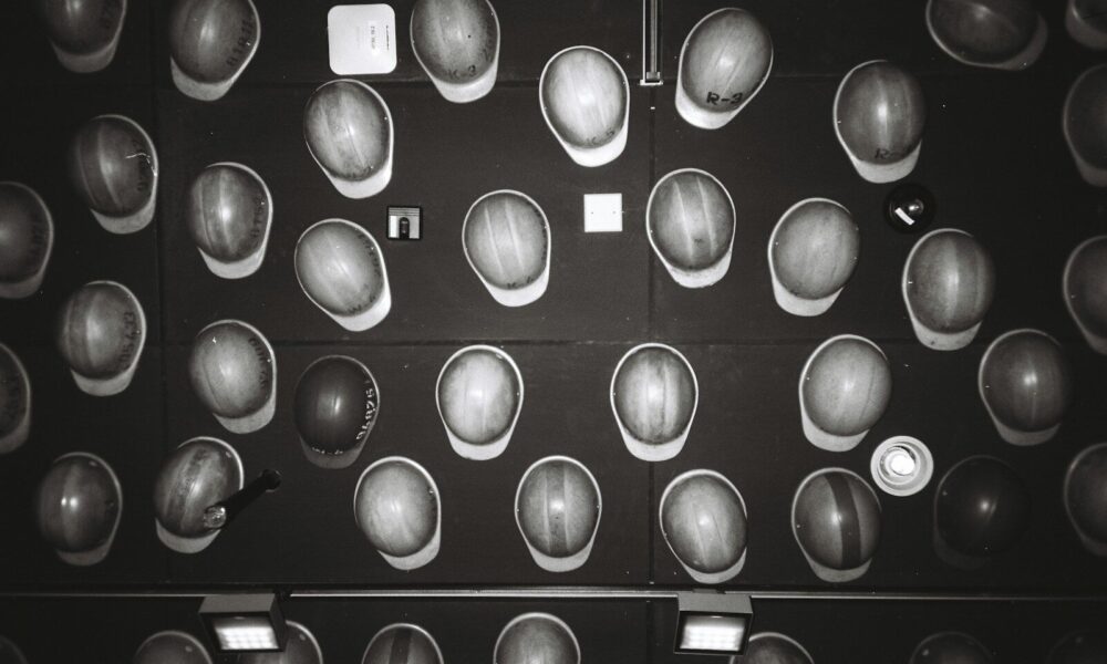 Many hard hats arranged on a dark wall.
