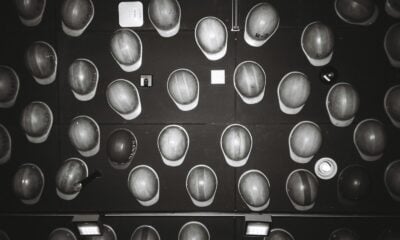 Many hard hats arranged on a dark wall.