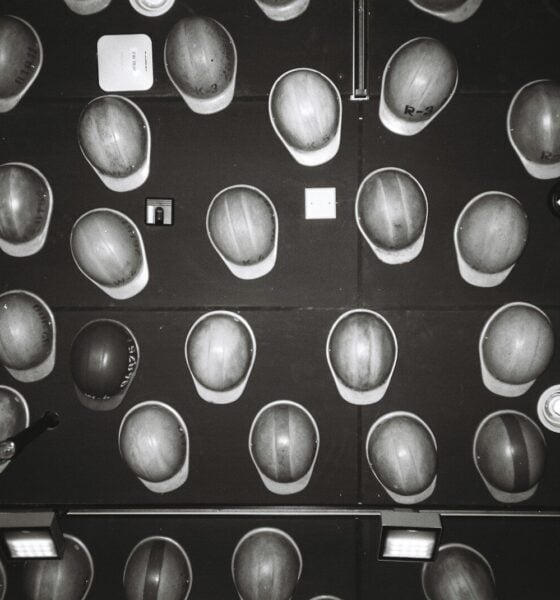 Many hard hats arranged on a dark wall.