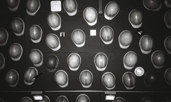 Many hard hats arranged on a dark wall.