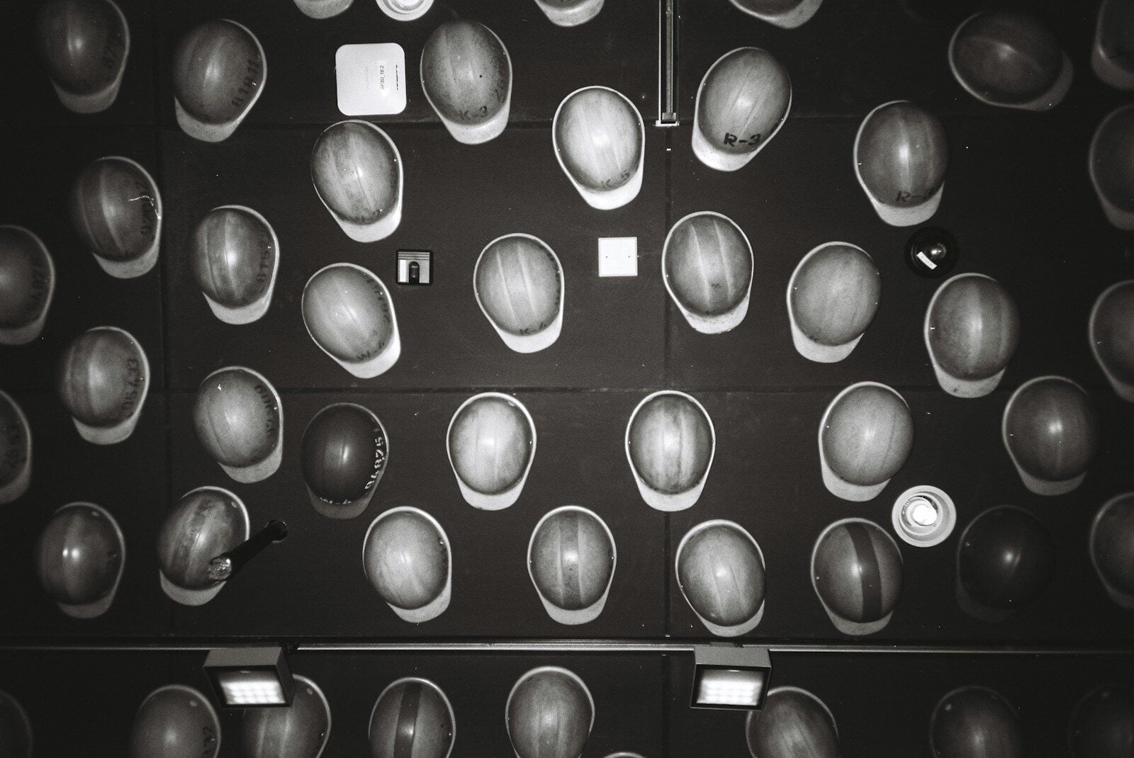 Many hard hats arranged on a dark wall.