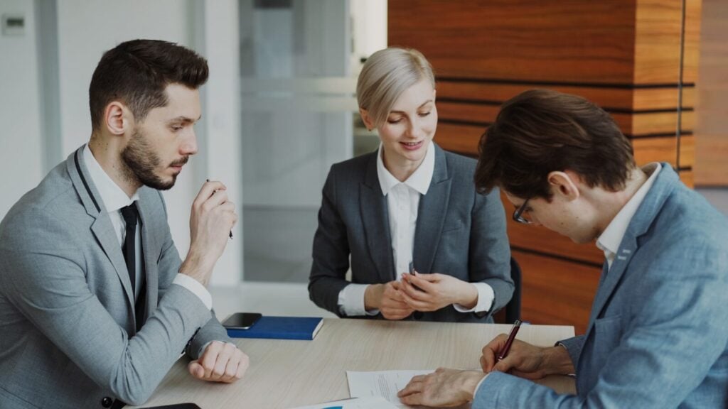 Business Formation Lawyer: Everything You Need to Know 28 Business people signing a contract at a table.