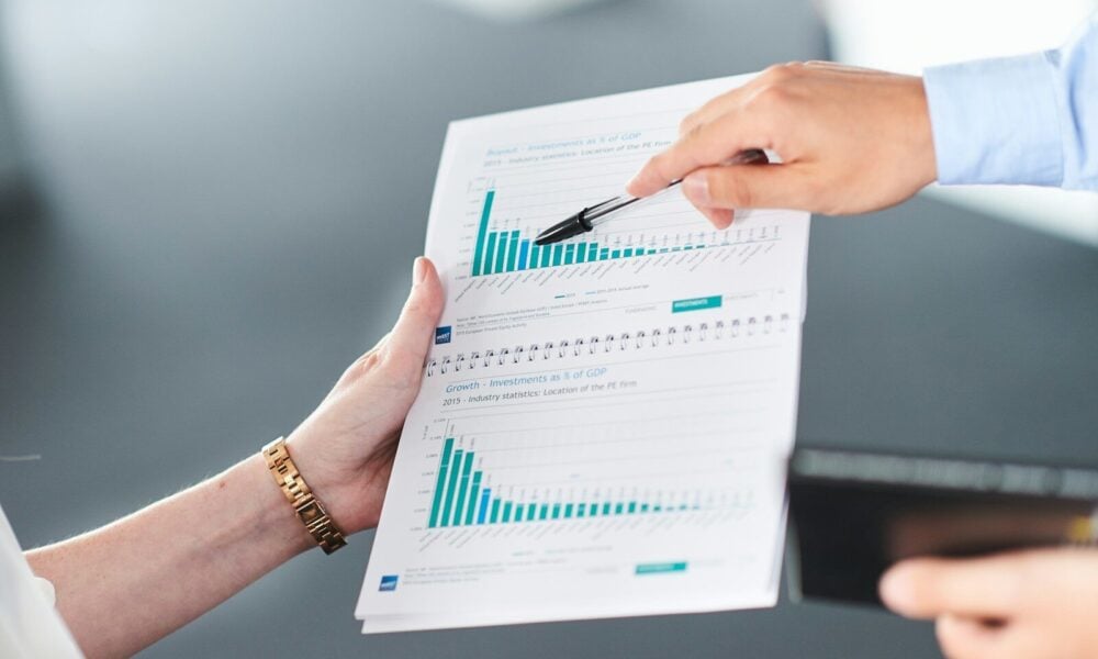 Two people analyzing a document with green bar charts.