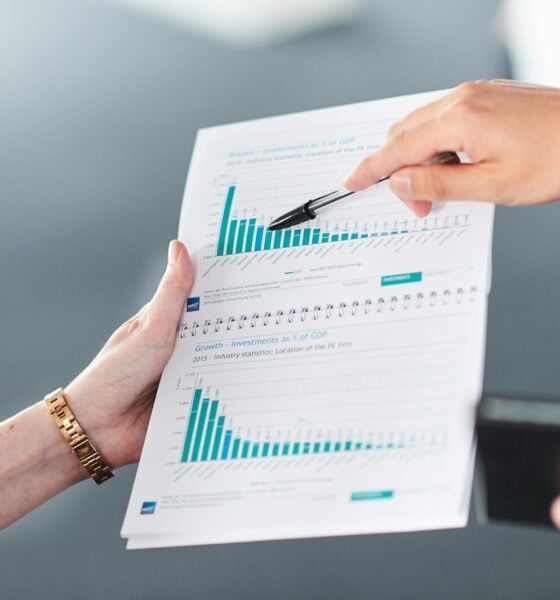 Two people analyzing a document with green bar charts.