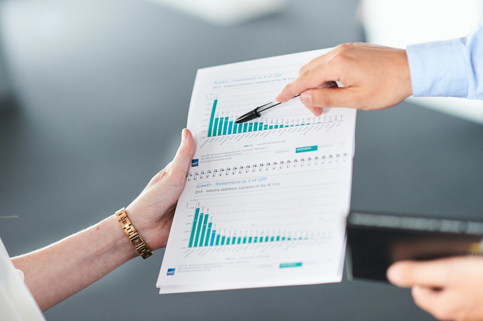 Two people analyzing a document with green bar charts.