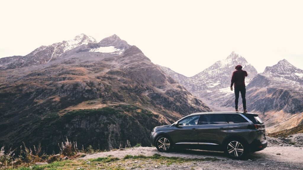Inhouse Vehicle Finance: How It Works and What to Expect 28 man standing on black 5-door hatchback across brown glacier mountains