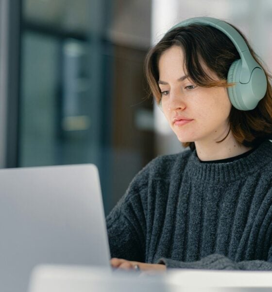 A woman sitting at a table with a laptop wearing headphones