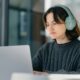 A woman sitting at a table with a laptop wearing headphones