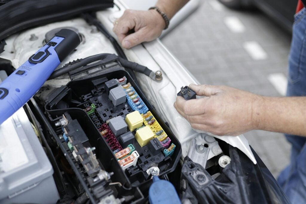 Vehicle Electrical Repair: Common Problems, Costs, and Solutions 28 a man is working on a car's engine