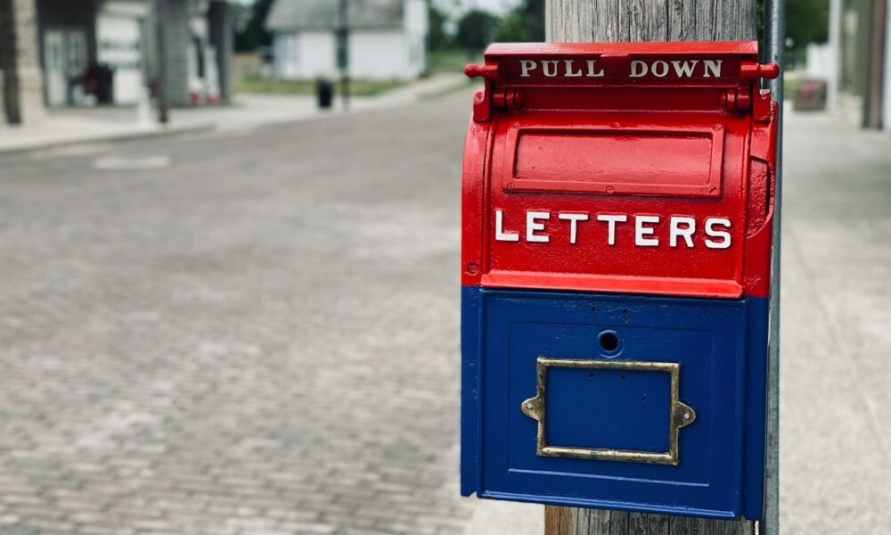 red mail box on brown wooden post