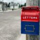 red mail box on brown wooden post