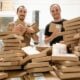 a couple of men standing next to a pile of boxes