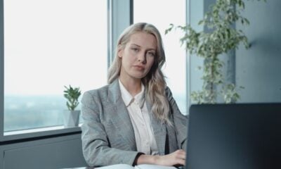 Professional businesswoman at a desk in a bright office with a laptop and notebook.