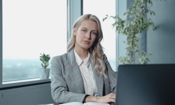 Professional businesswoman at a desk in a bright office with a laptop and notebook.