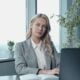 Professional businesswoman at a desk in a bright office with a laptop and notebook.
