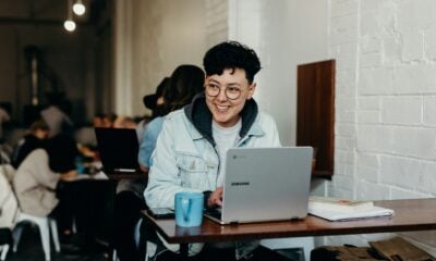 smiling man sitting and using Samsung laptop near people
