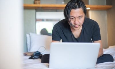 An Asian man working from home on a laptop, focusing on his digital tasks in a cozy indoor setting.
