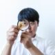 Close-up of a man examining a Bitcoin coin with a magnifying glass, symbolizing cryptocurrency analysis.