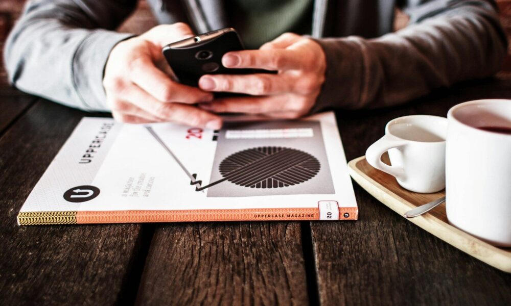 person holding black Android smartphone while leaning on table