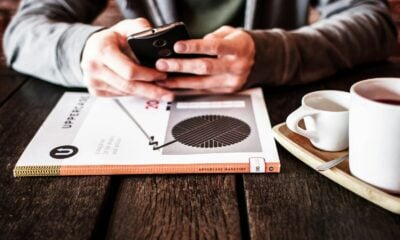 person holding black Android smartphone while leaning on table