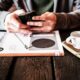person holding black Android smartphone while leaning on table