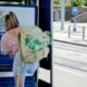 A woman with a backpack is using a public payphone