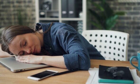 a woman laying her head on a laptop