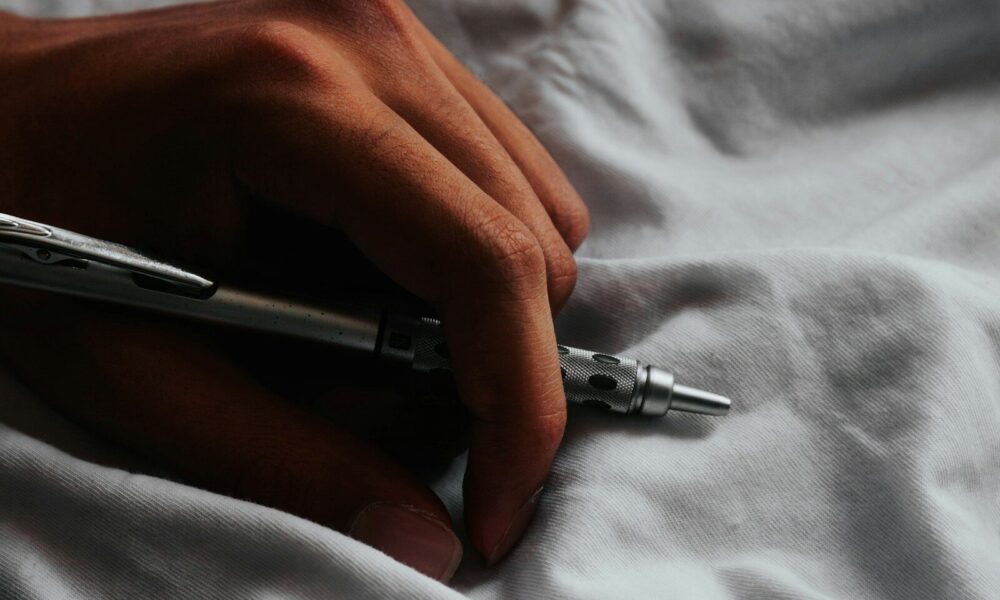 a person writing on a sheet with a pen