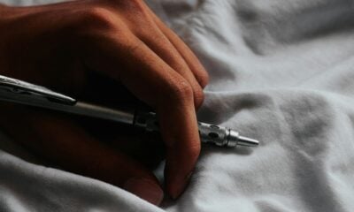 a person writing on a sheet with a pen