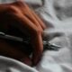 a person writing on a sheet with a pen