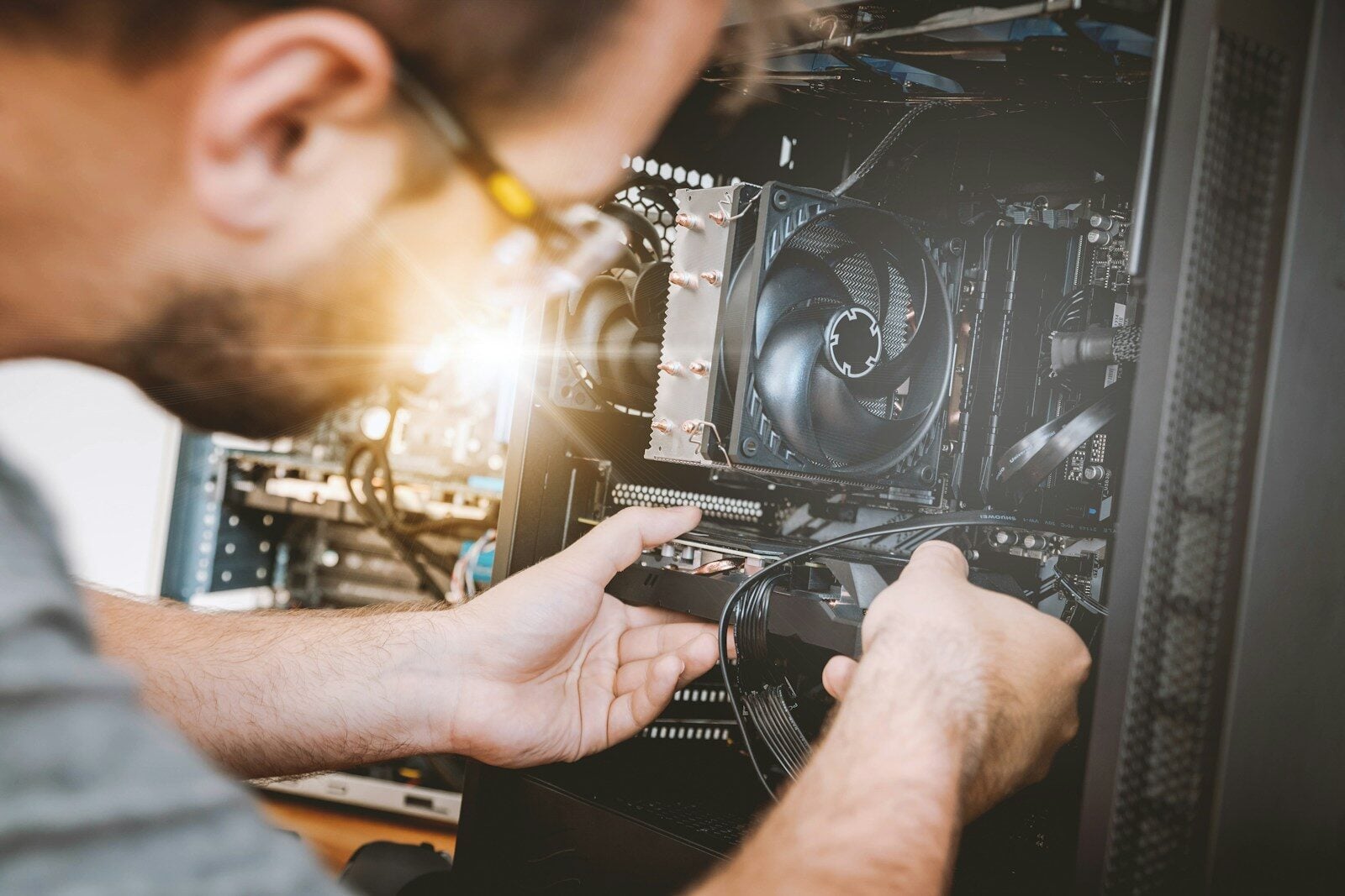 A person installing a graphics card into a computer case with a cooling fan