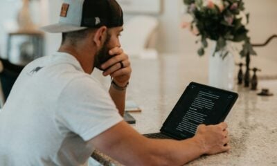 man in white t-shirt using black laptop computer