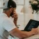man in white t-shirt using black laptop computer