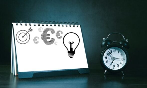 Desk calendar with business symbols and alarm clock