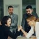 Two women arm wrestling with men watching