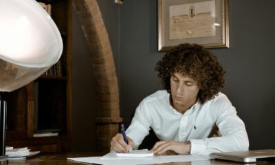 woman in white dress shirt holding pen writing on white paper