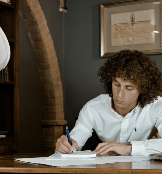 woman in white dress shirt holding pen writing on white paper